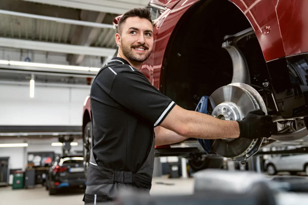 Bilmekanikere arbeider i verkstedet med å justere hjulakselen på en opphengt bil.